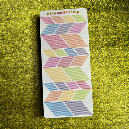 Colorful geometric patterned sticker sheet on a green textured surface