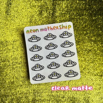 Sheet of black silhouette stickers on a white card with 'neon mothership' branding, against a green textured background.