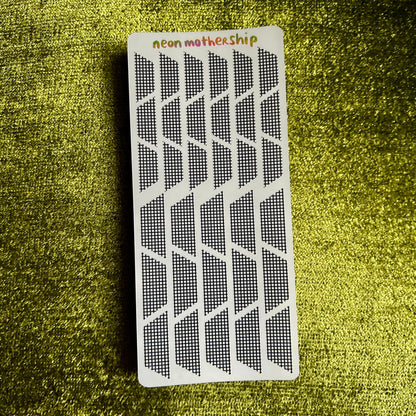 Rectangular sticker sheet with geometric stickers on a textured green surface