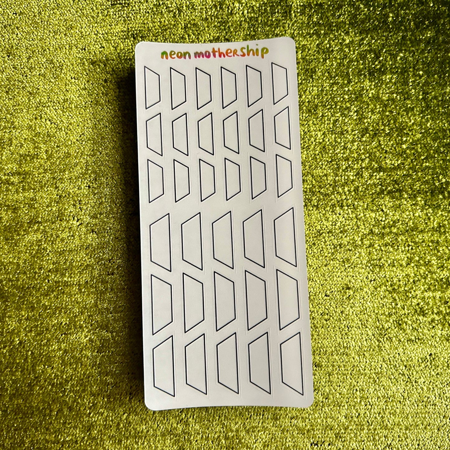 Sheet of geometric stickers labeled 'Neon Mothership' on a green textured surface