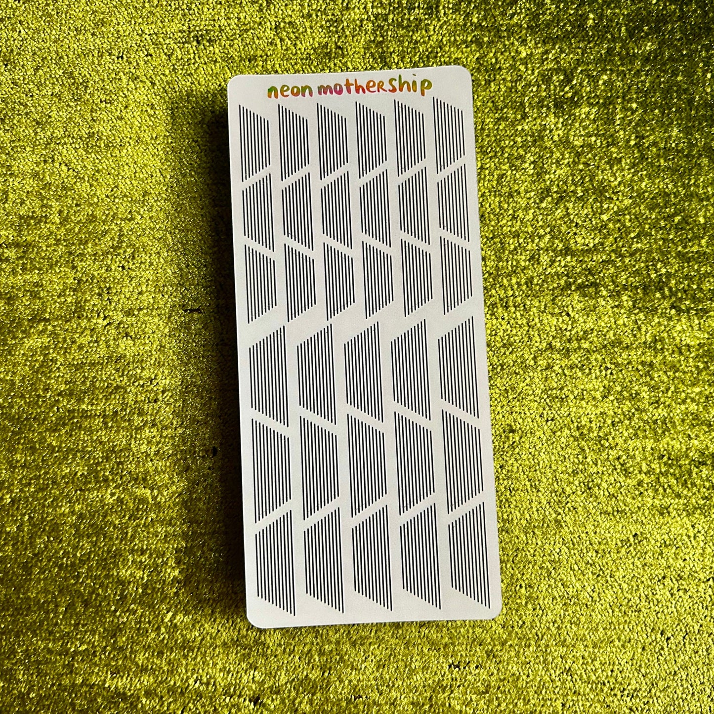 Rectangular sticker sheet with grid pattern on a green textured surface