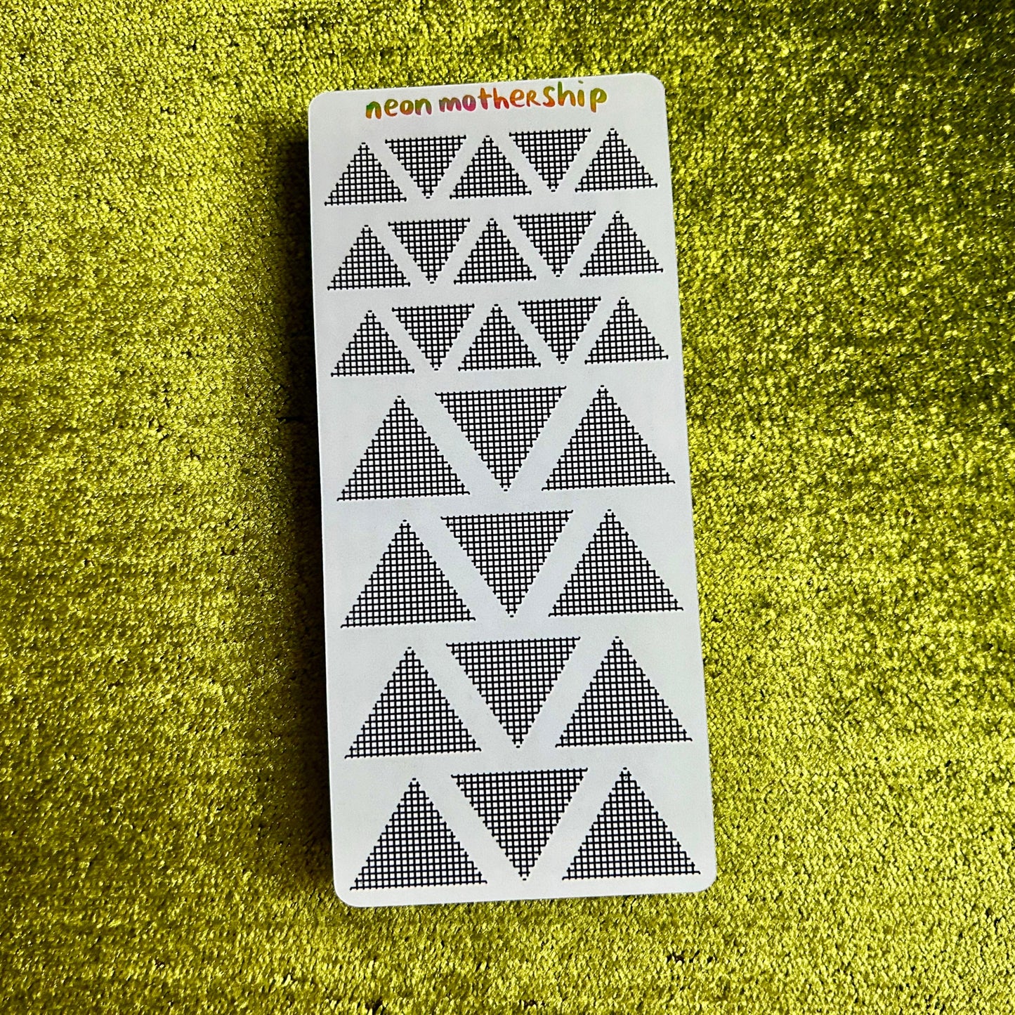 sticker sheet with triangular geometric pattern on a green textured surface
