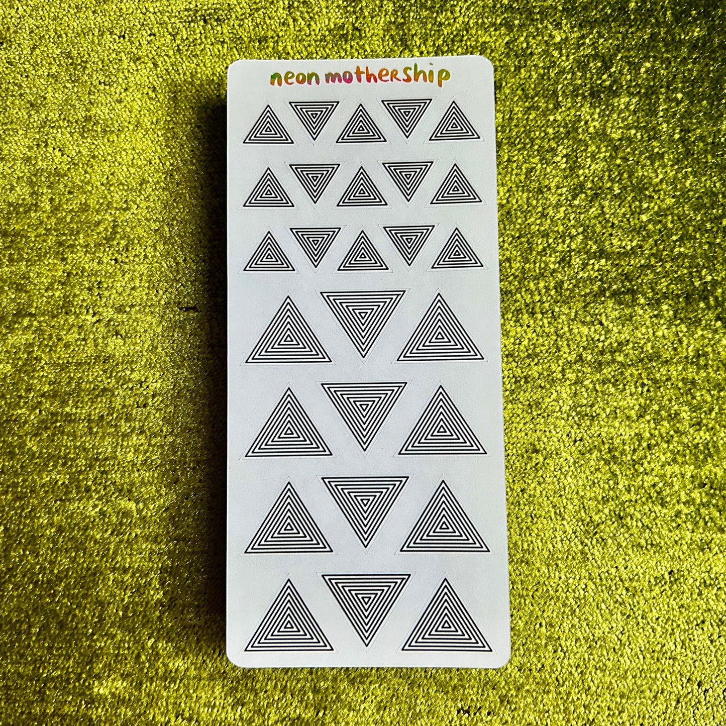 sticker sheet with geometric triangle pattern on a textured green surface