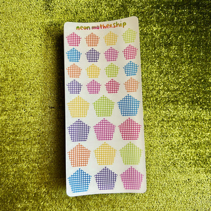 Pack of colorful pentagon stickers on a green textured surface