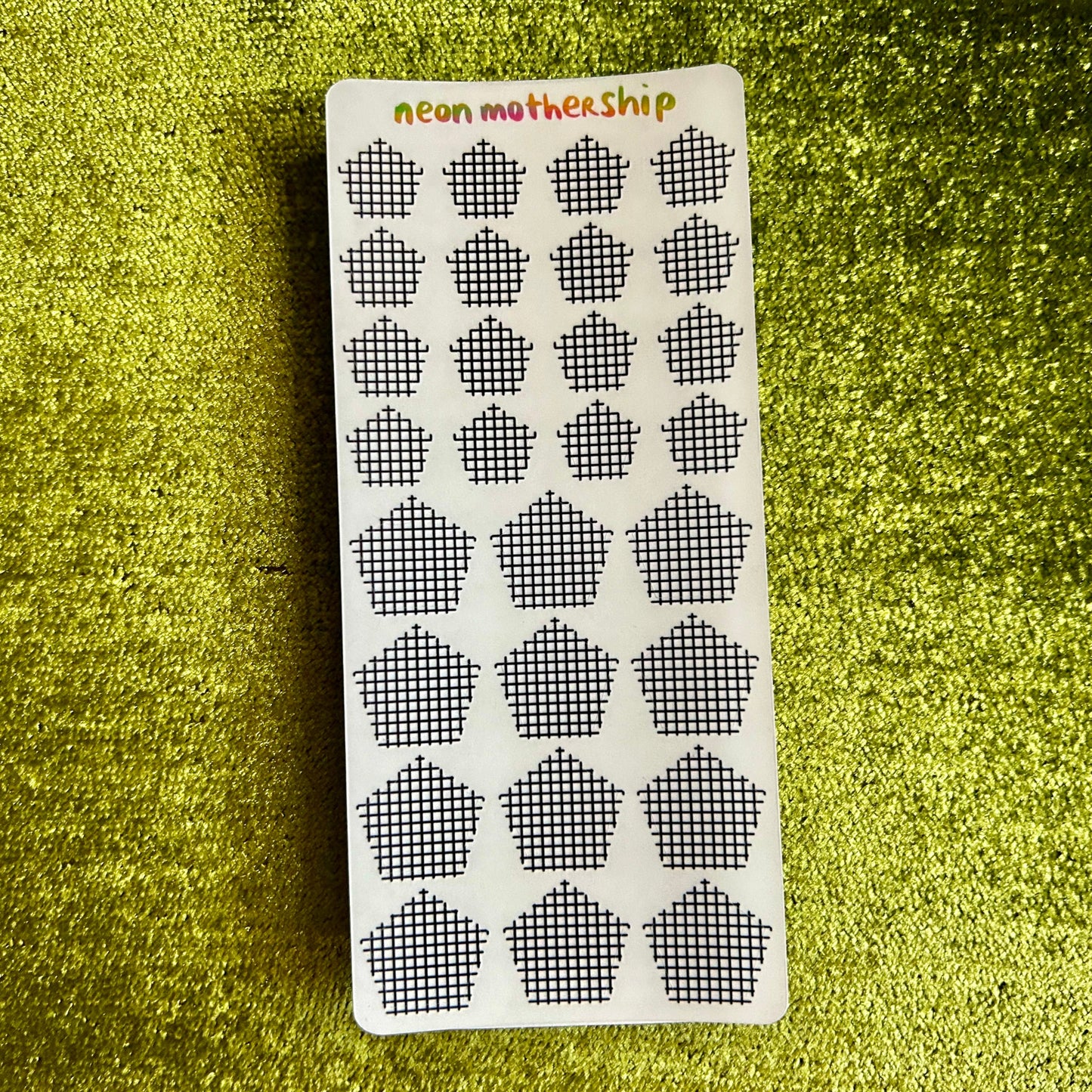 Sheet of black and white grid stickers on a green textured background