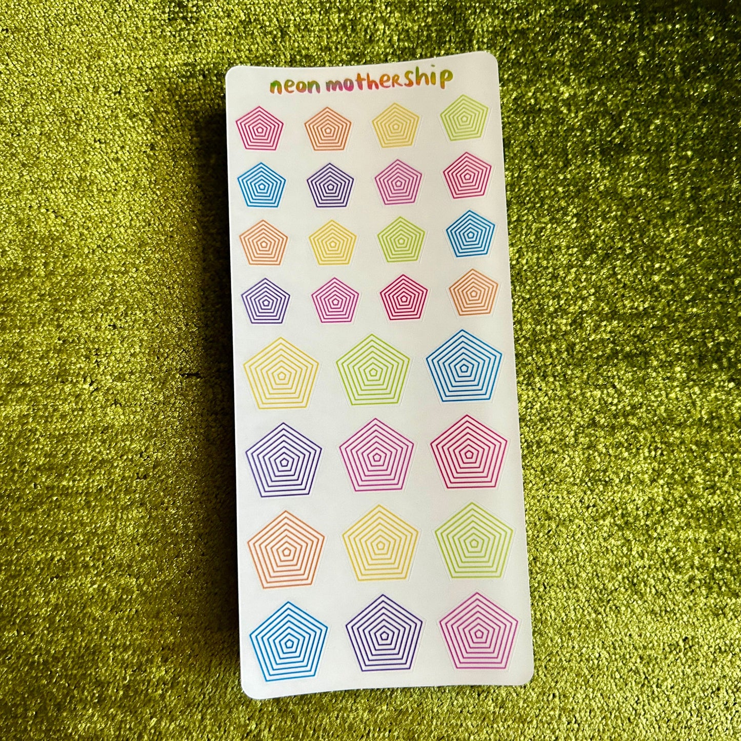 Sheet of colorful geometric stickers on a green textured background