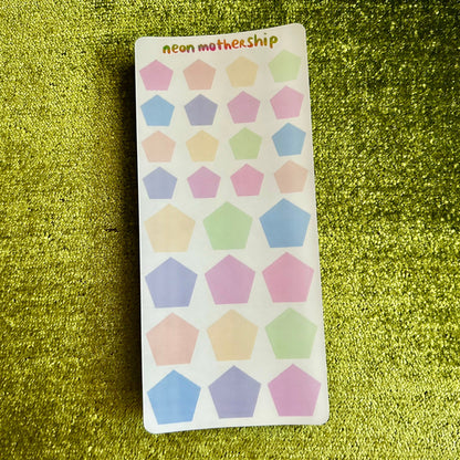 Sheet of colorful pentagon shaped stickers on a green glittery background
