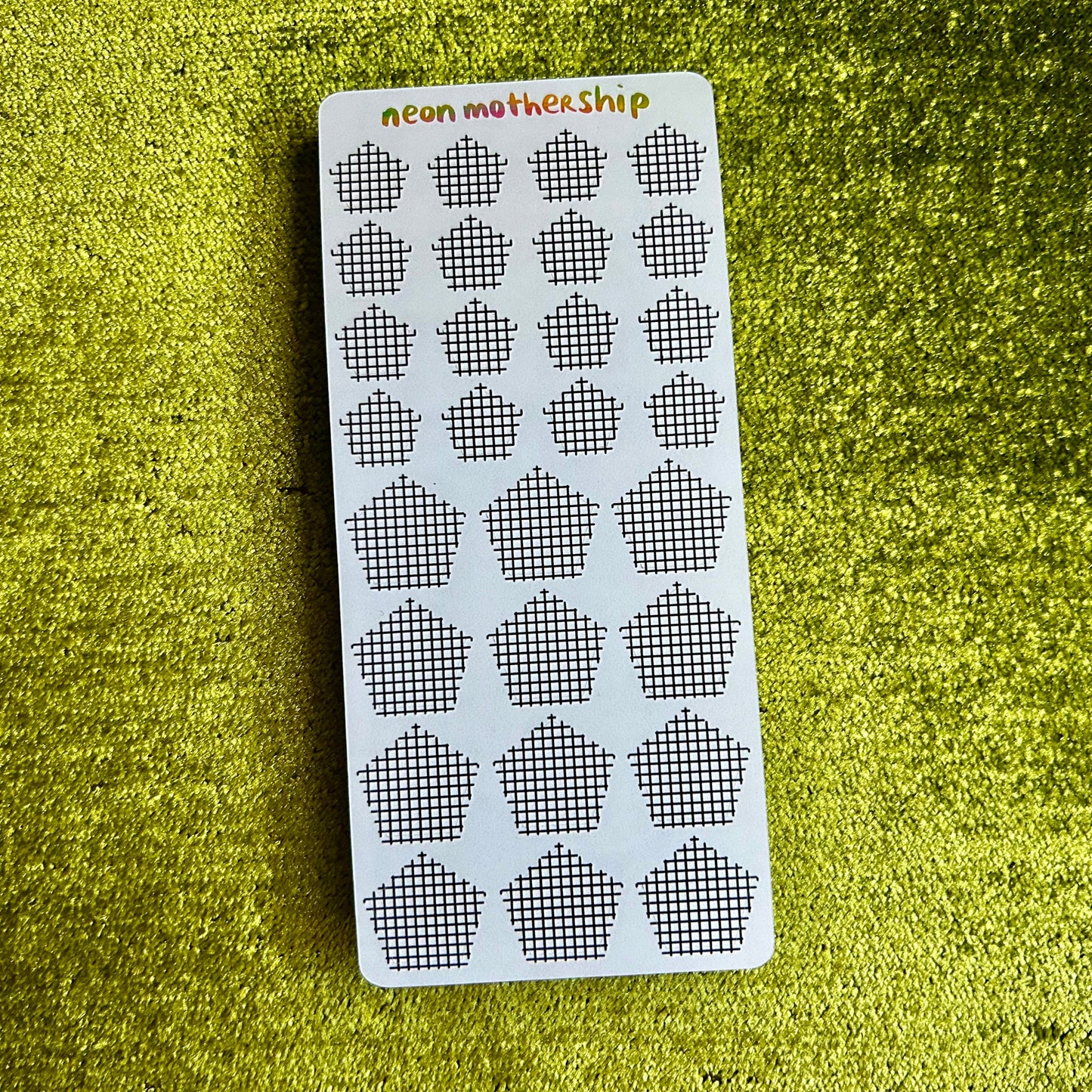 Sheet of black and white patterned stickers on a green textured surface