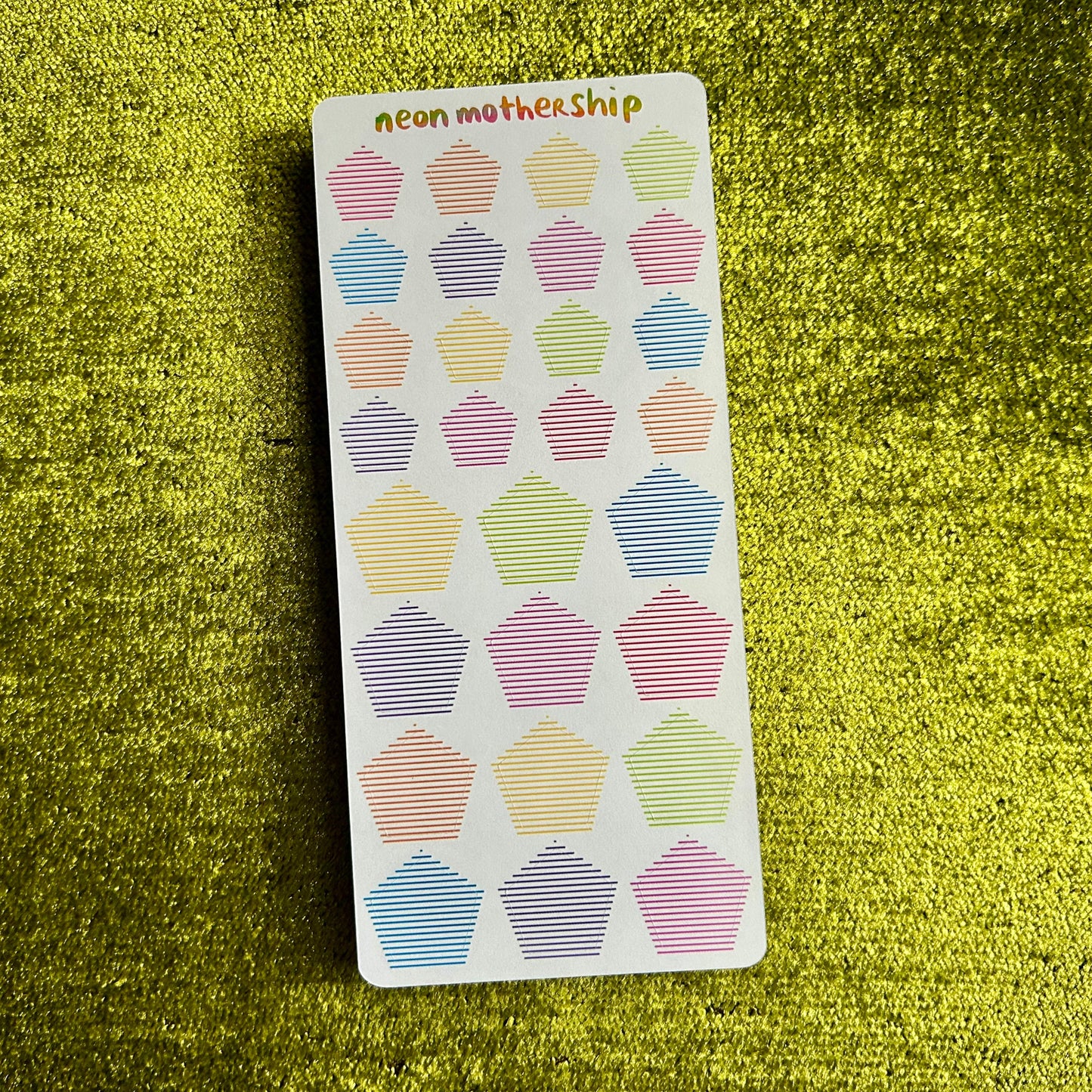 Sticker sheet with pentagon designs on a green textured surface