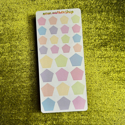 Sticker sheet with pentagon designs on a green textured surface