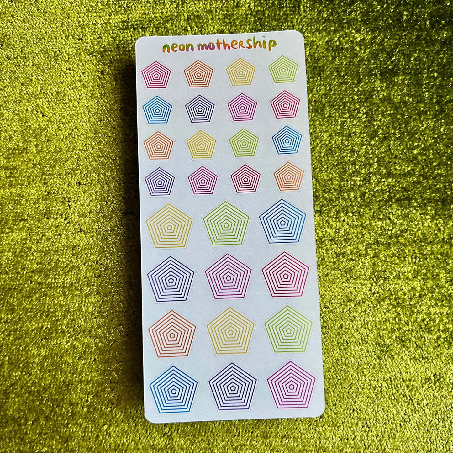 Pack of colorful geometric stickers on a green textured surface