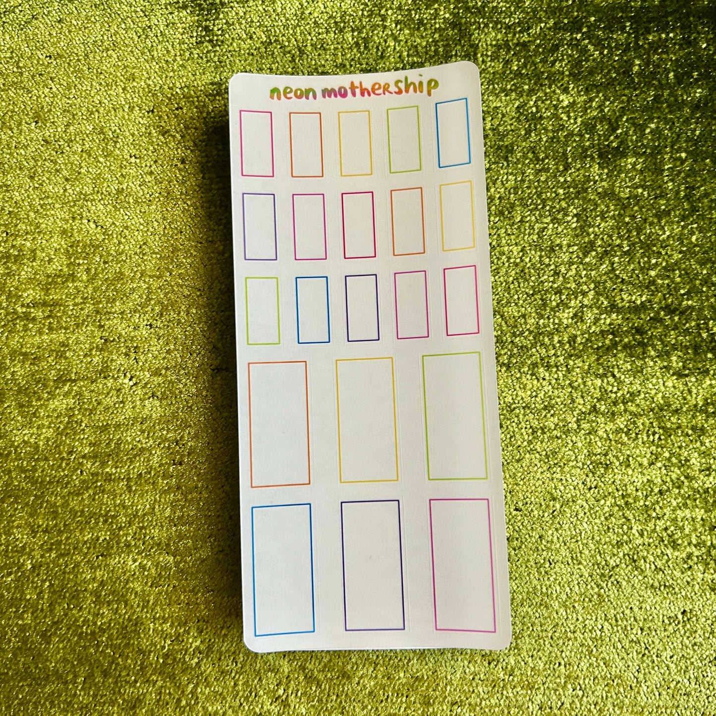 Sheet of colorful rectangular stickers on a green textured background