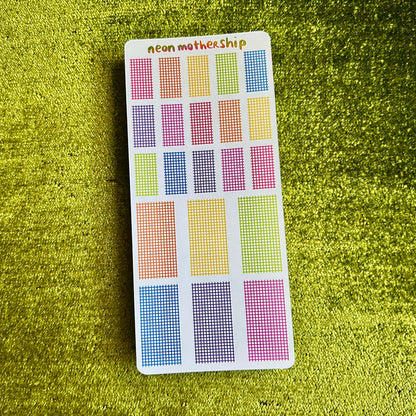 Colorful grid patterned stickers on a green textured surface