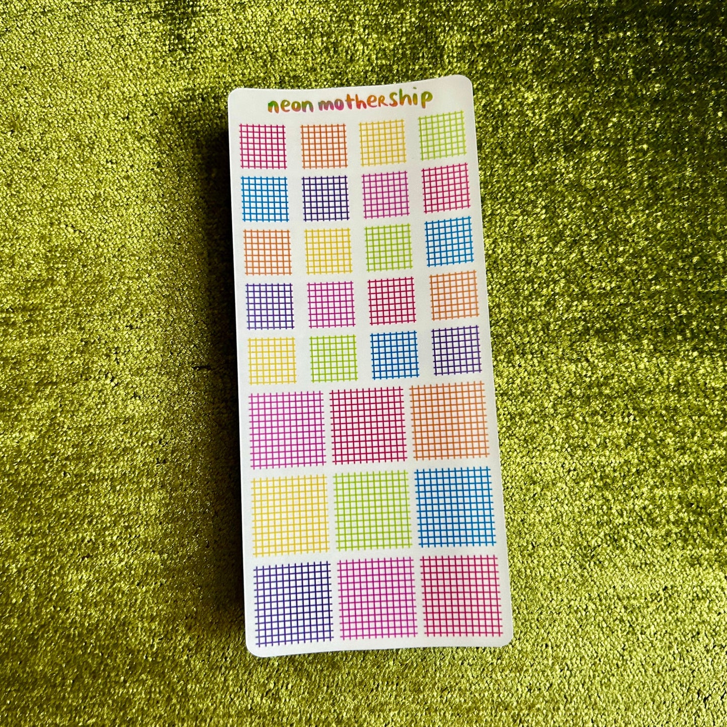 sticker sheet with grid of squares on a green textured surface