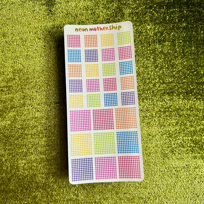 sticker sheet with grid of squares on a green textured surface