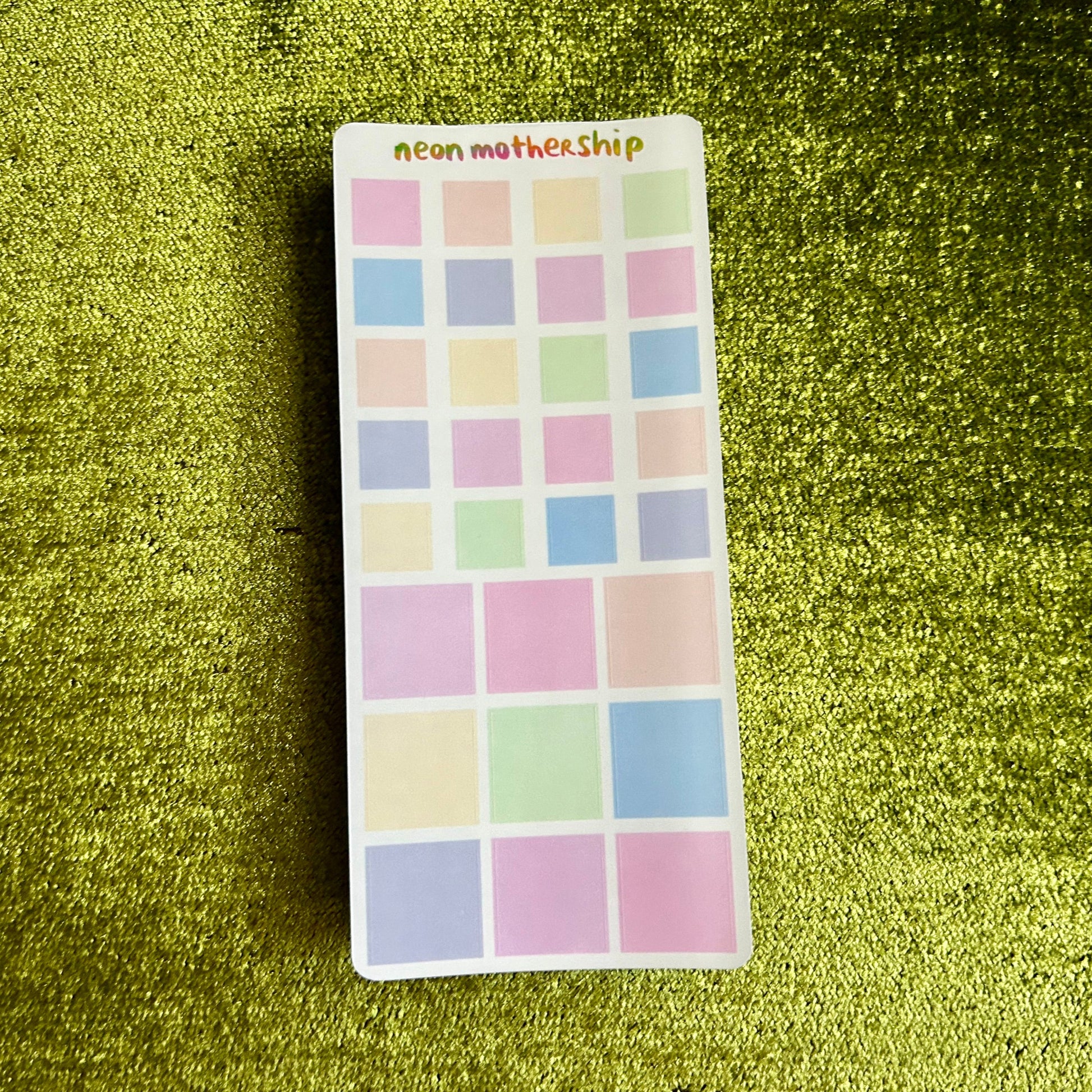 sticker sheet with pastel square stickers on a green textured background