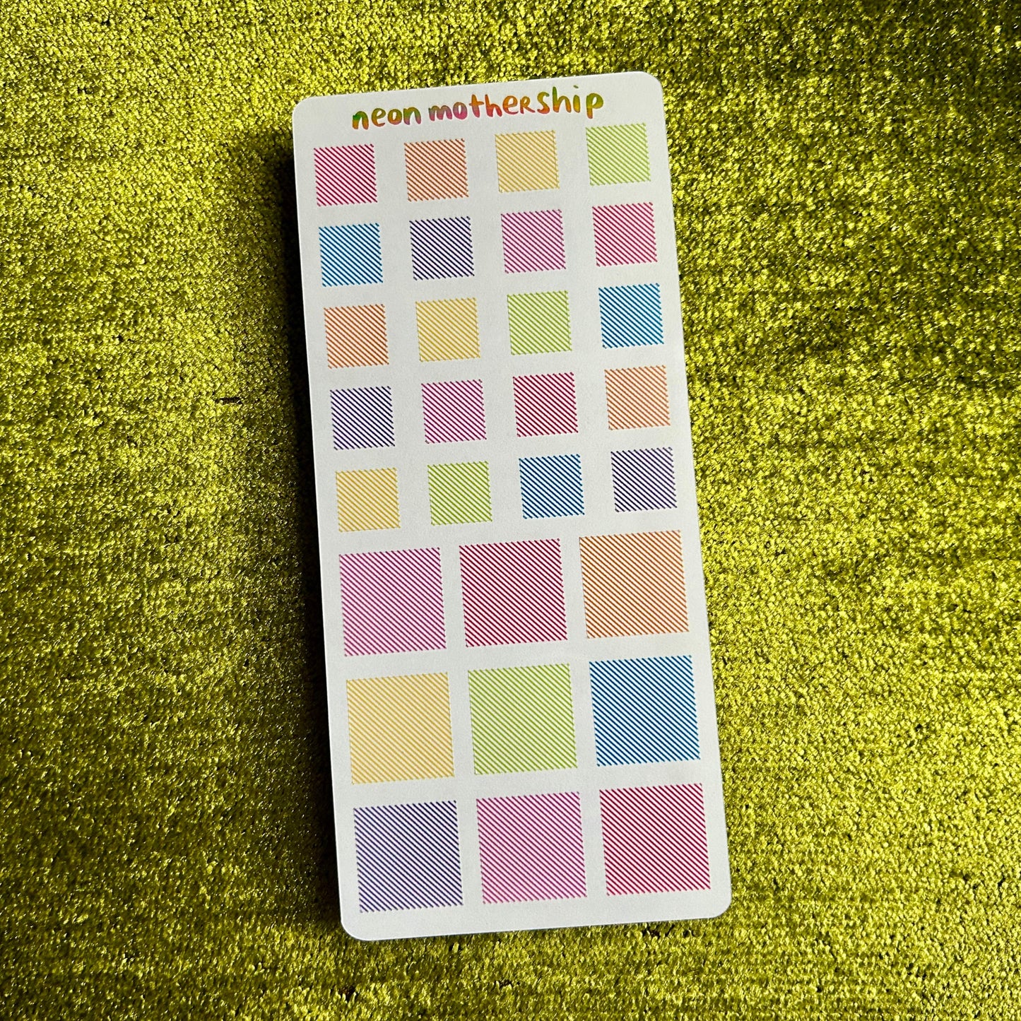sticker sheet with pastel squares on a green textured surface