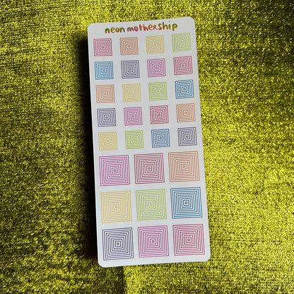 Pack of colorful square stickers on a green textured surface