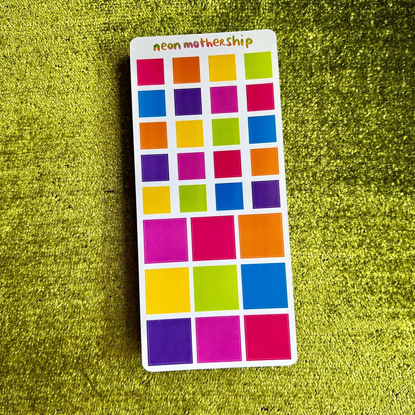 Color swatch sticker with squares in various colors on a green textured background