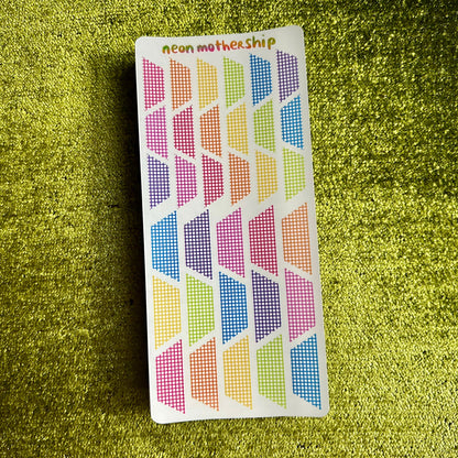 Colorful geometric patterned grid stickers on a green textured surface