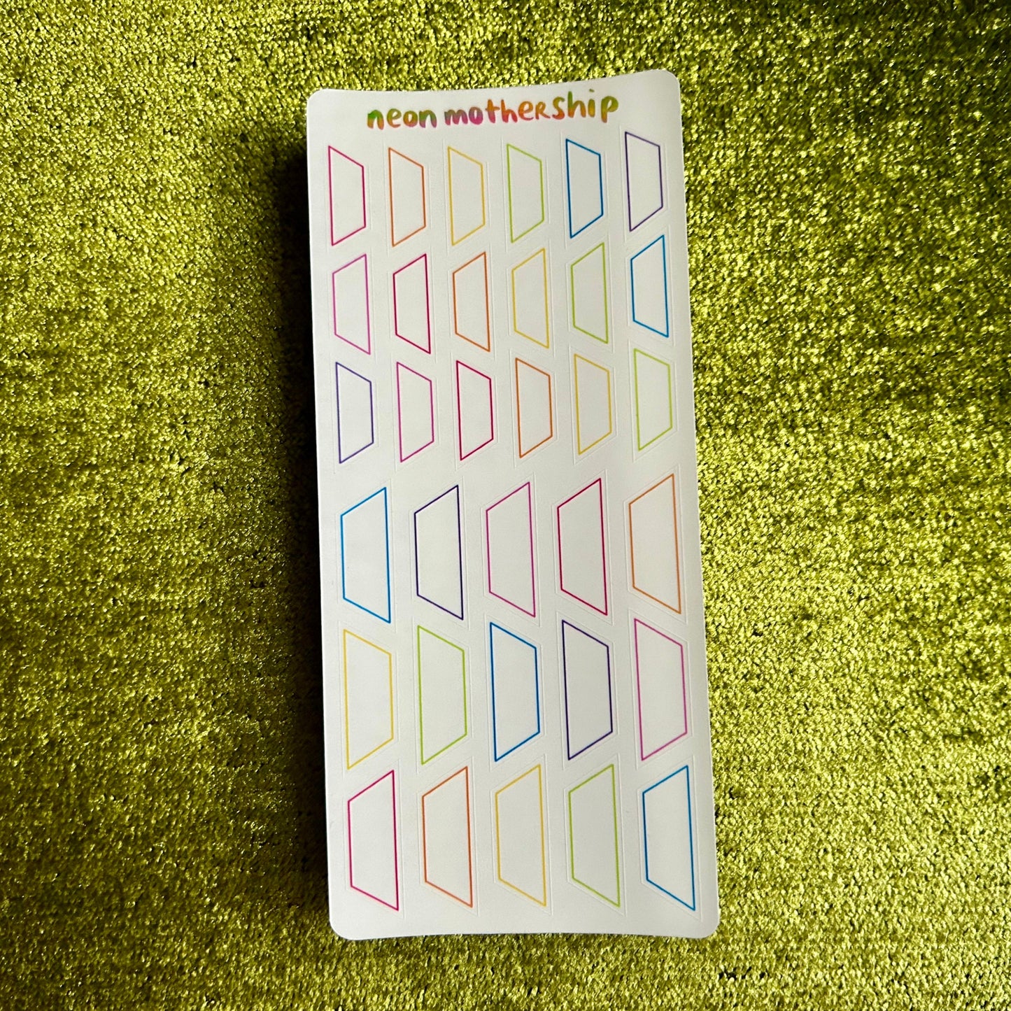 Sheet of colorful geometric stickers on a green glittery background
