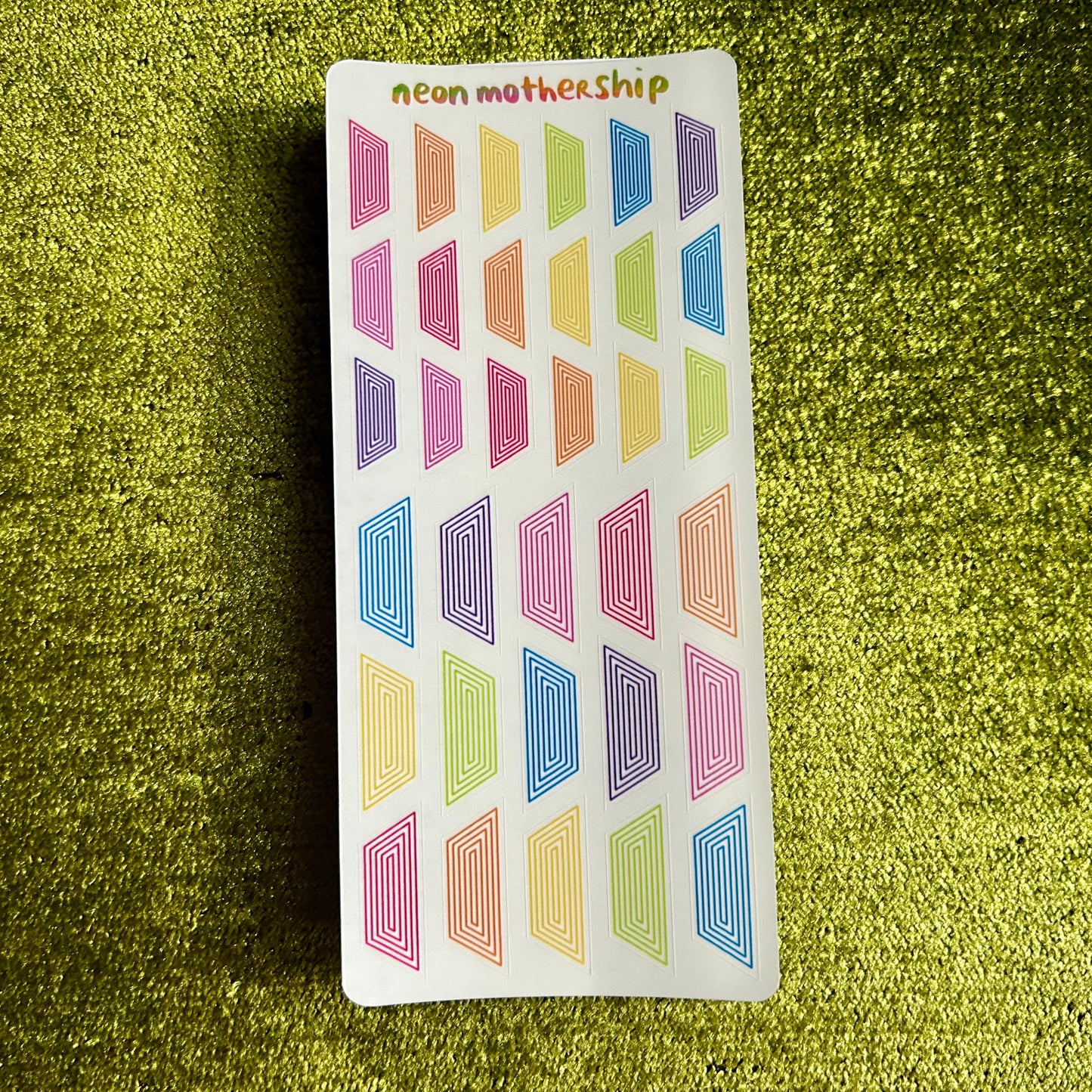 Colorful geometric patterned stickers on a green textured surface
