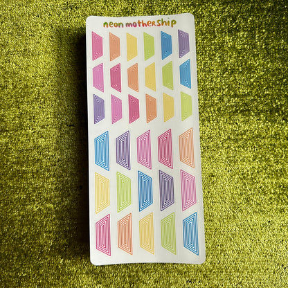 Colorful geometric patterned stickers on a green textured surface