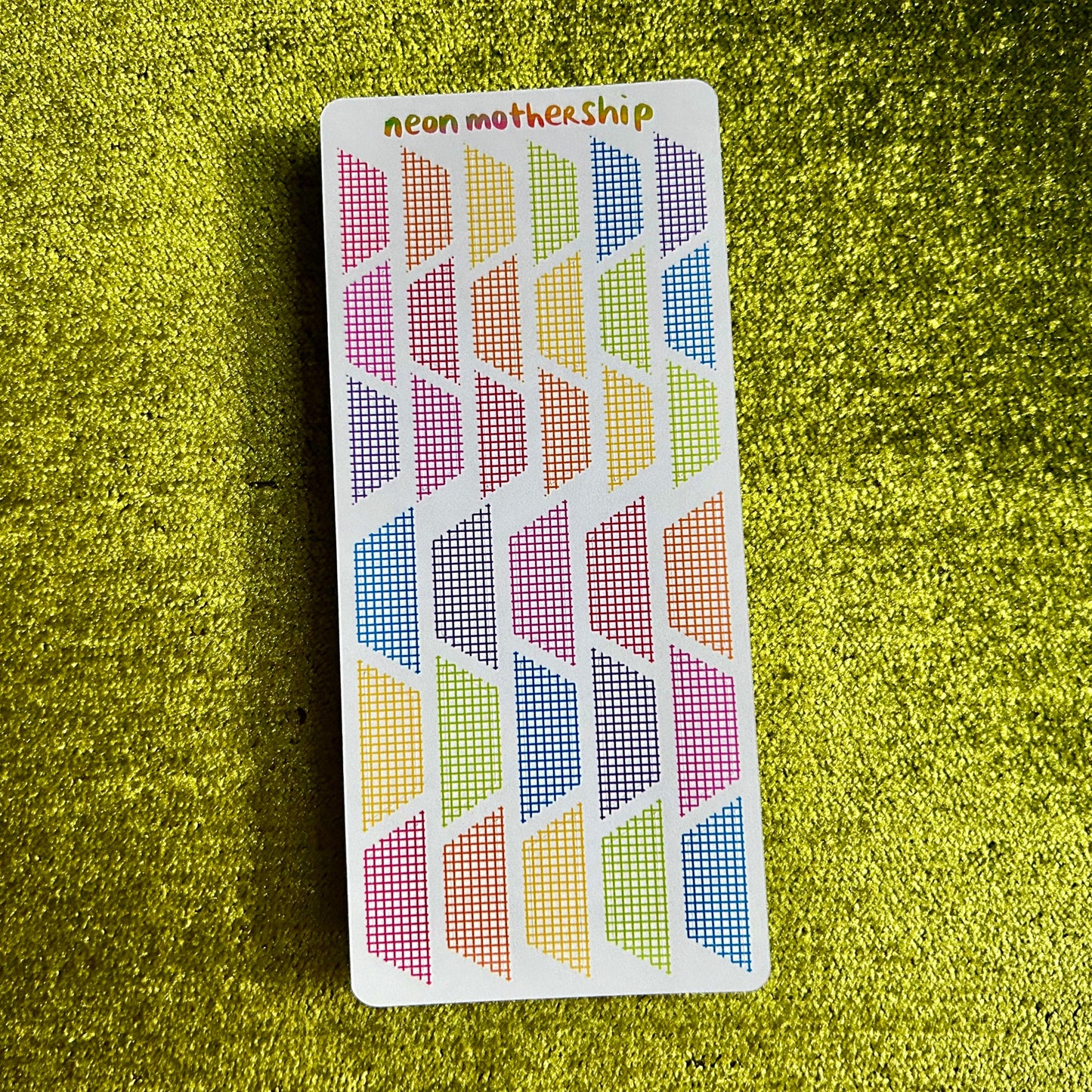 Colorful geometric patterned sticker sheet on a green textured surface