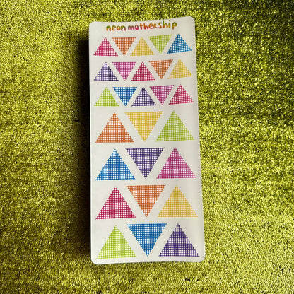 Sticker sheet with colorful triangle patterns on a green textured surface