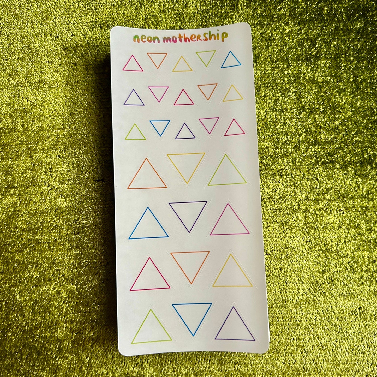 Sheet of colorful triangle stickers on a green textured background