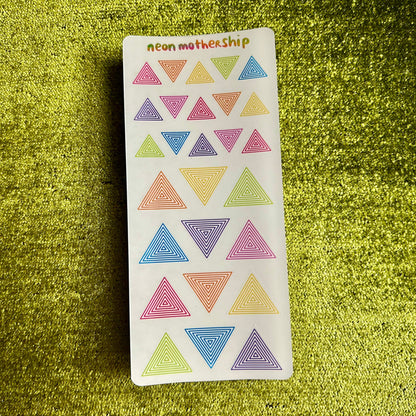 Pack of colorful triangle stickers with 'neon mothership' branding on a green textured background.