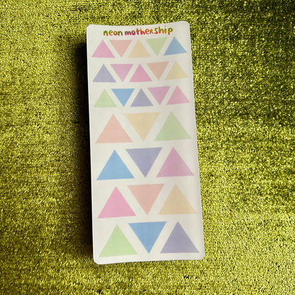 Pack of colorful triangle stickers on a green textured surface