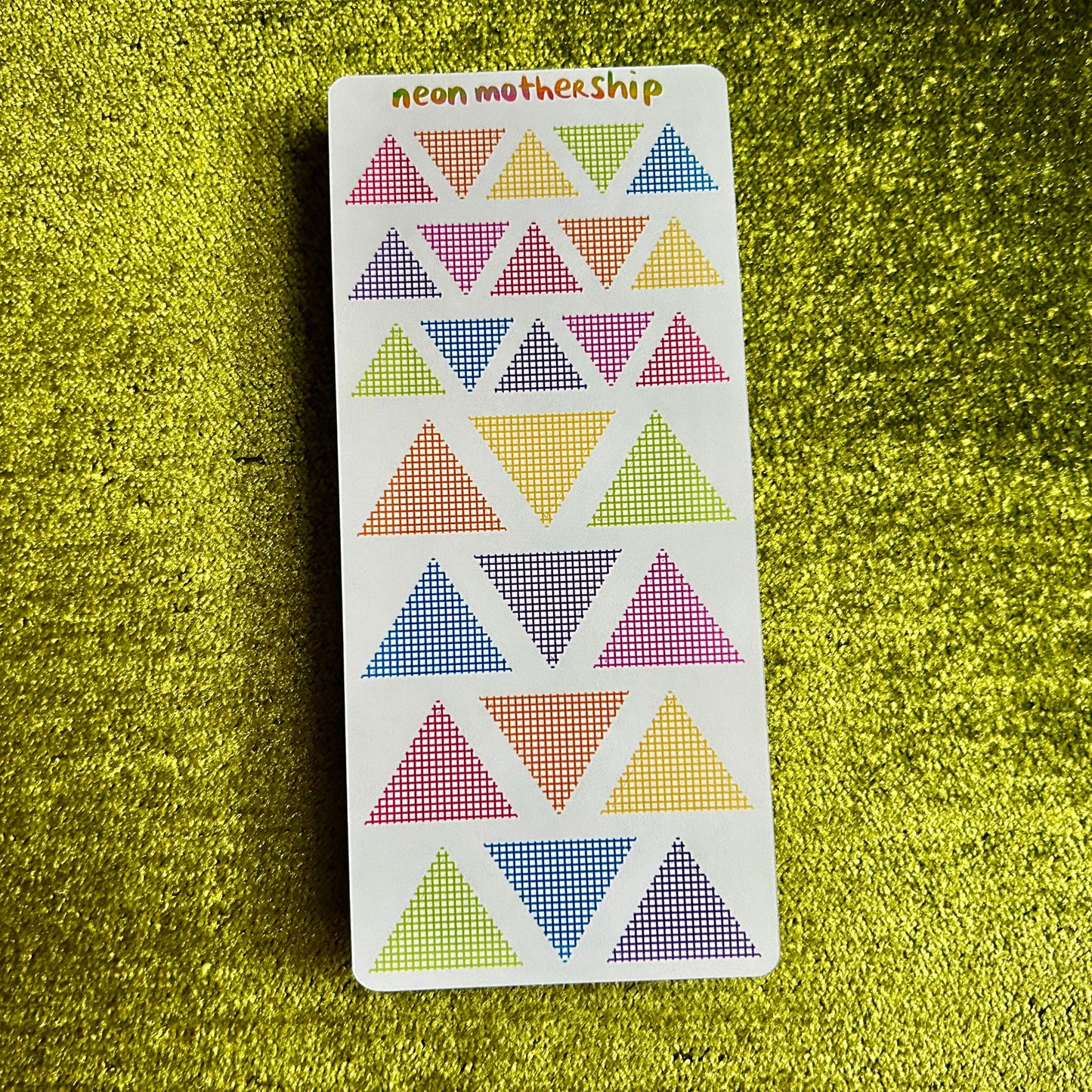 Card with colorful triangle stickers on a green textured surface