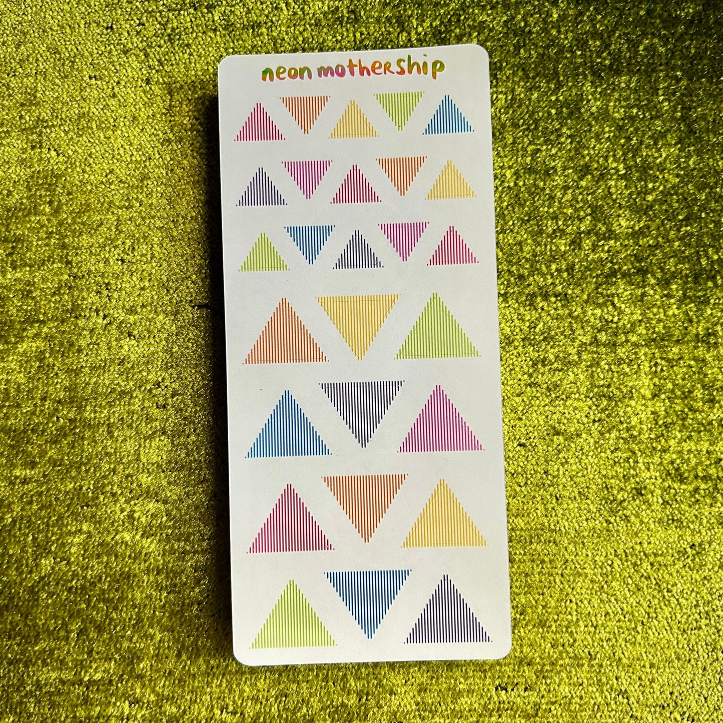 Card with colorful triangle stickers on a green textured surface