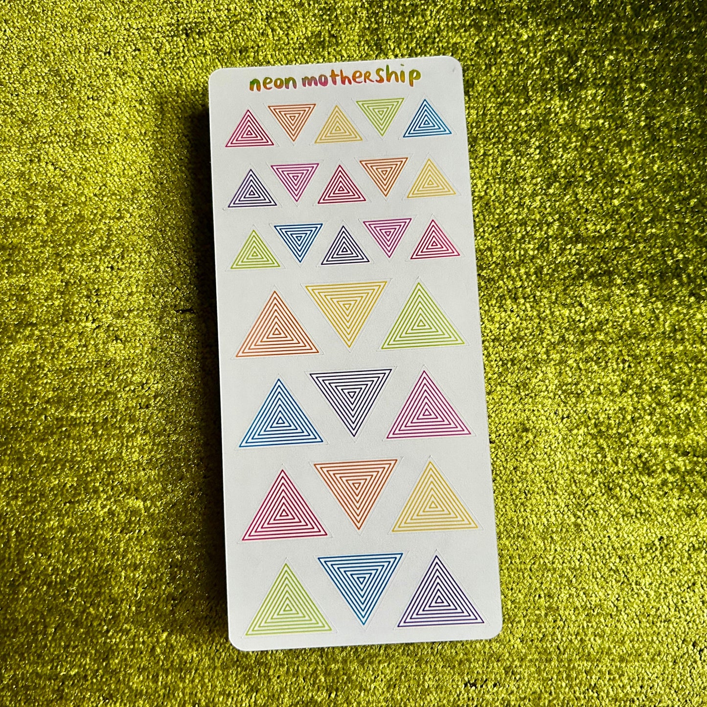 Card with colorful triangle stickers on a green textured surface