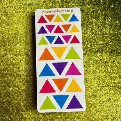 Colorful triangle pattern on a white card with 'neon mothership' branding, against a green textured background.